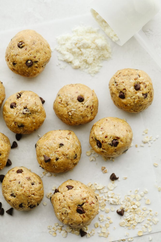 Protein balls are a delicious no-bake treat! Start your new year right by snacking on these tasty, healthy bites loaded with chocolate chips and peanut butter! Chocolate chip protein balls laid out on parchment paper.