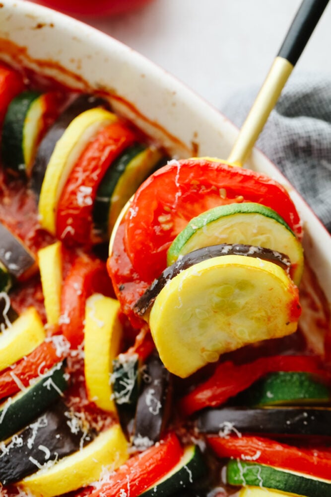 This ratatouille is made up of delicious sliced vegetables that are seasoned to perfection and cooked in a delicious sauce. It's so good that you will want to add it as a side to every meal! Cooked ratatouille being dished with a spoon.
