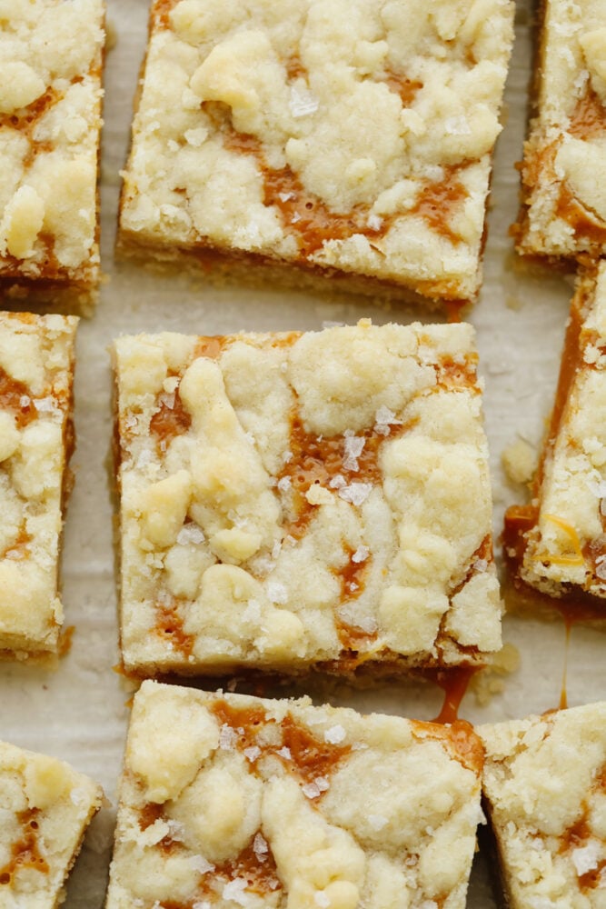 Salted caramel butter bars are the perfect easy-to-make dessert. With a buttery and crumbly shortbread crust that is topped with a smooth layer of caramel, there will be a little bit of sweet and savory in each bite! Salted caramel butter bars on a baking sheet cut up.