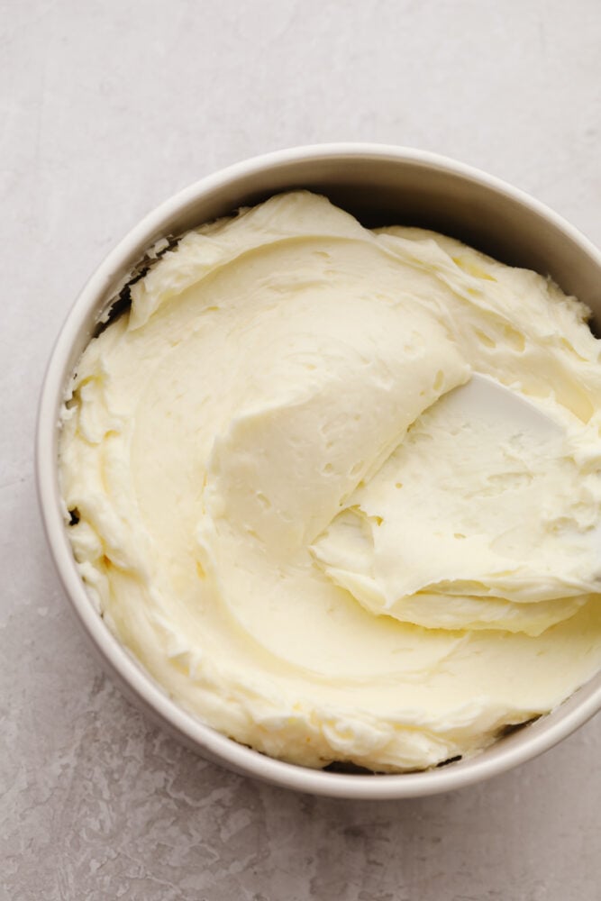 This smooth and creamy white chocolate buttercream is perfect for all of your favorite cakes and cupcakes! You'll want this silky frosting on everything! White chocolate buttercream frosting in a white bowl.