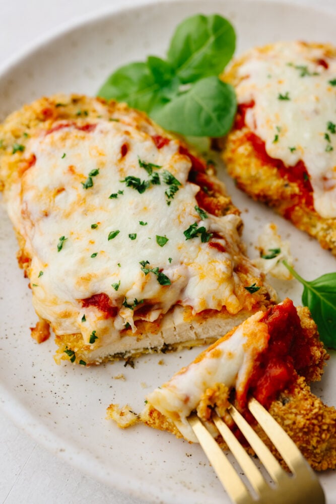 Air fryer chicken parmesan is cheesy, crispy, and cooks up in less than 10 minutes! It’s an easy-to-make dinner that your family will go crazy over! Closeup of a bite of chicken parmesan.