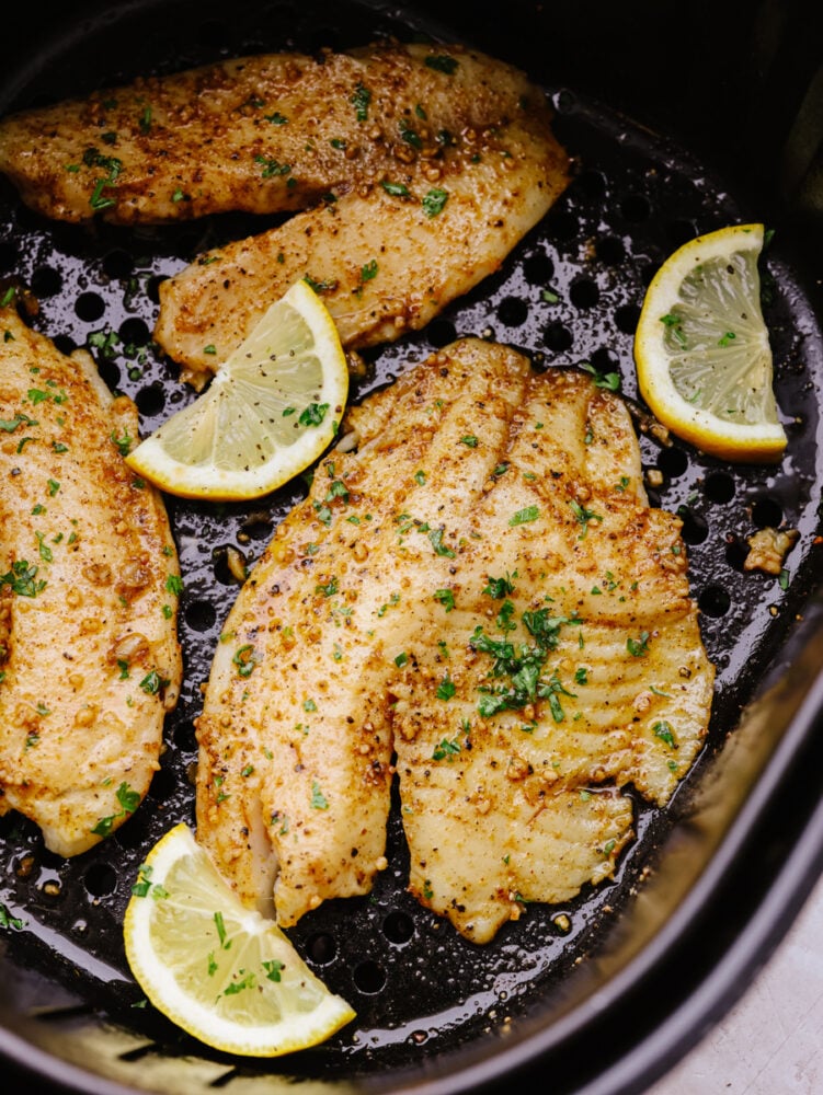 Using an air fryer and Cajun spices is the best way to cook up this tender fish! This air fryer cajun garlic butter tilapia is so easy and delicious, it's sure to become a new favorite lunch! Cooked Cajun tilapia in the basket of an air fryer.