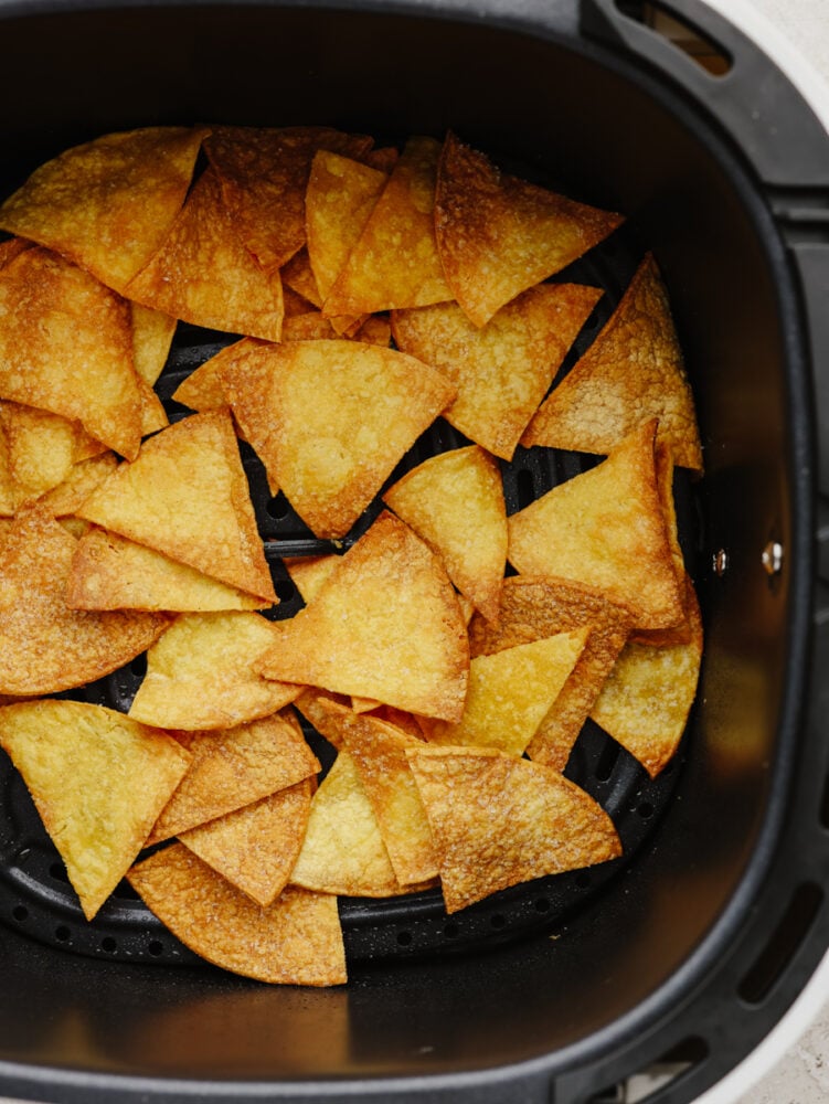 Air fryer tortilla chips are the perfect addition to all of your favorite salsas and dips! Once you try homemade chips, you won't want them any other way! Homemade tortilla chips in the basket of an air fryer.