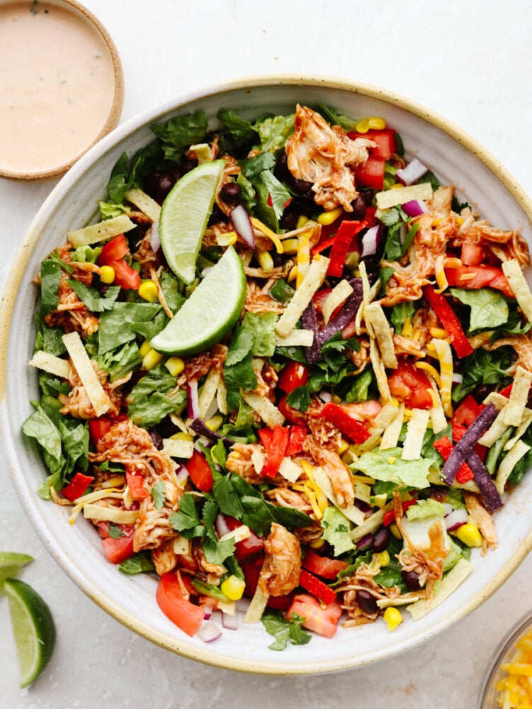 This BBQ chicken salad is healthy and packed to the brim with flavor! Filled with veggies, shredded chicken, and crispy tortilla chips, this salad really takes off when you add in the dressing. It's to die for! A bowl of BBQ chicken salad.