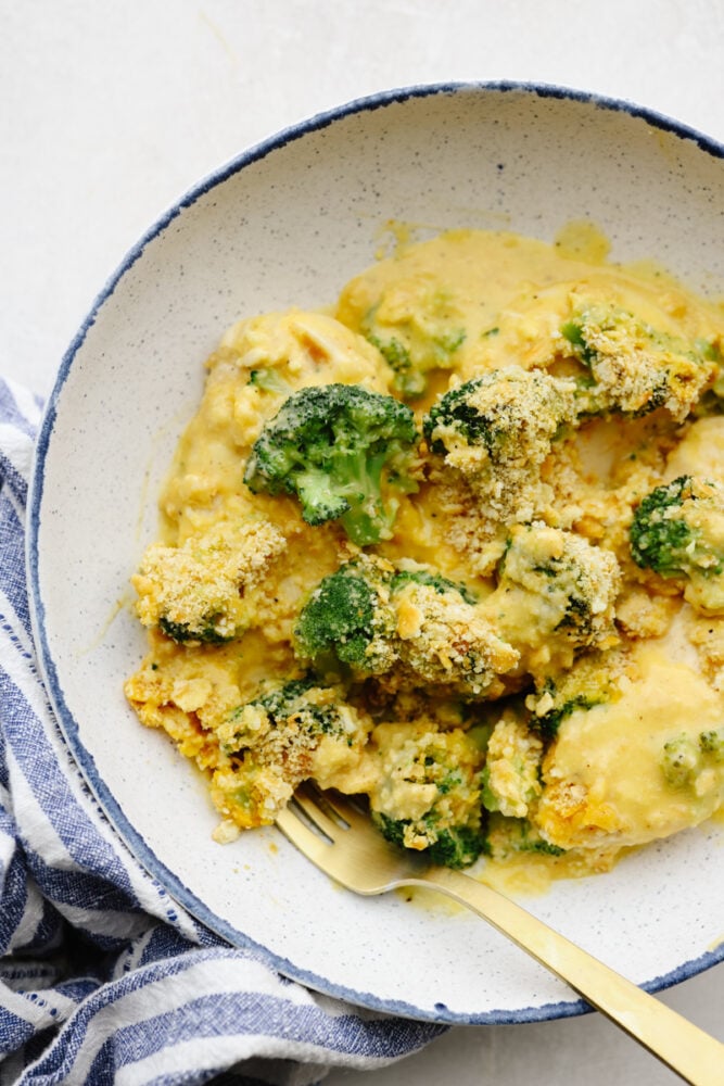 Comfort food at its finest, this broccoli cheddar chicken will fill you right up! Insanely delicious and straightforward to make, this is a dinner your entire family will go crazy over! Broccoli cheddar chicken cut up on a plate with a gold fork.