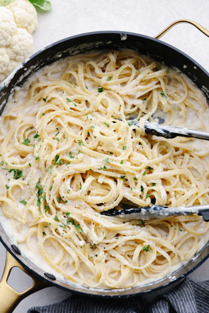 This cauliflower alfredo sauce is rich, creamy, and healthy! With this sauce, you get all of that insanely delicious flavor without the heavy cream. It's so good that you will want to put it on everything! A saucepan of fettucine alfredo.