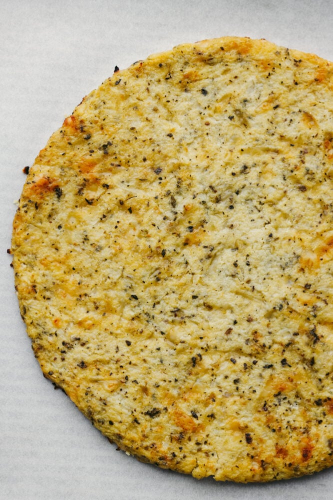 This cauliflower pizza crust is grain-free and absolutely delicious!! It's so easy to make and when you are done, you won't be able to even tell that it's the healthy version! It's THAT good! A cauliflower pizza crust all cooked and ready to go.