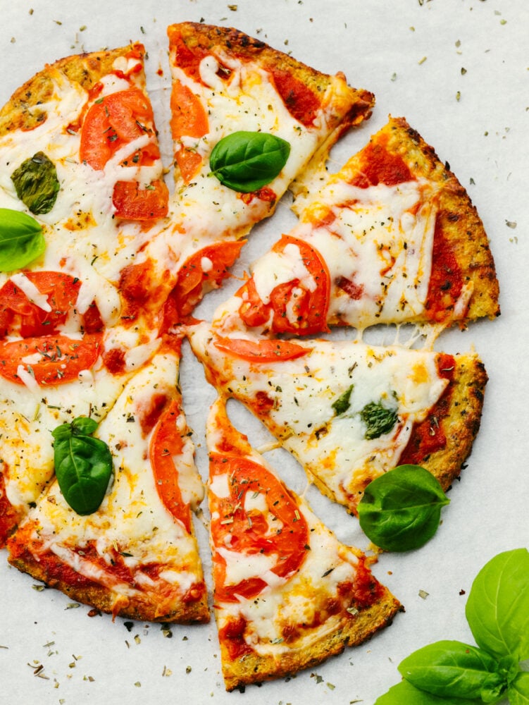This cauliflower pizza crust is grain-free and absolutely delicious!! It's so easy to make and when you are done, you won't be able to even tell that it's the healthy version! It's THAT good! A pizza with tomatoes, basil and a cauliflower crust.