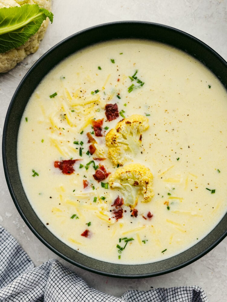 Cauliflower soup is so creamy and delicious. It's made from simple ingredients so that you can load it up with your favorite toppings or enjoy it on its own. It will be a hit with the entire family! A bowl of cauliflower soup garnished with chives and bacon.