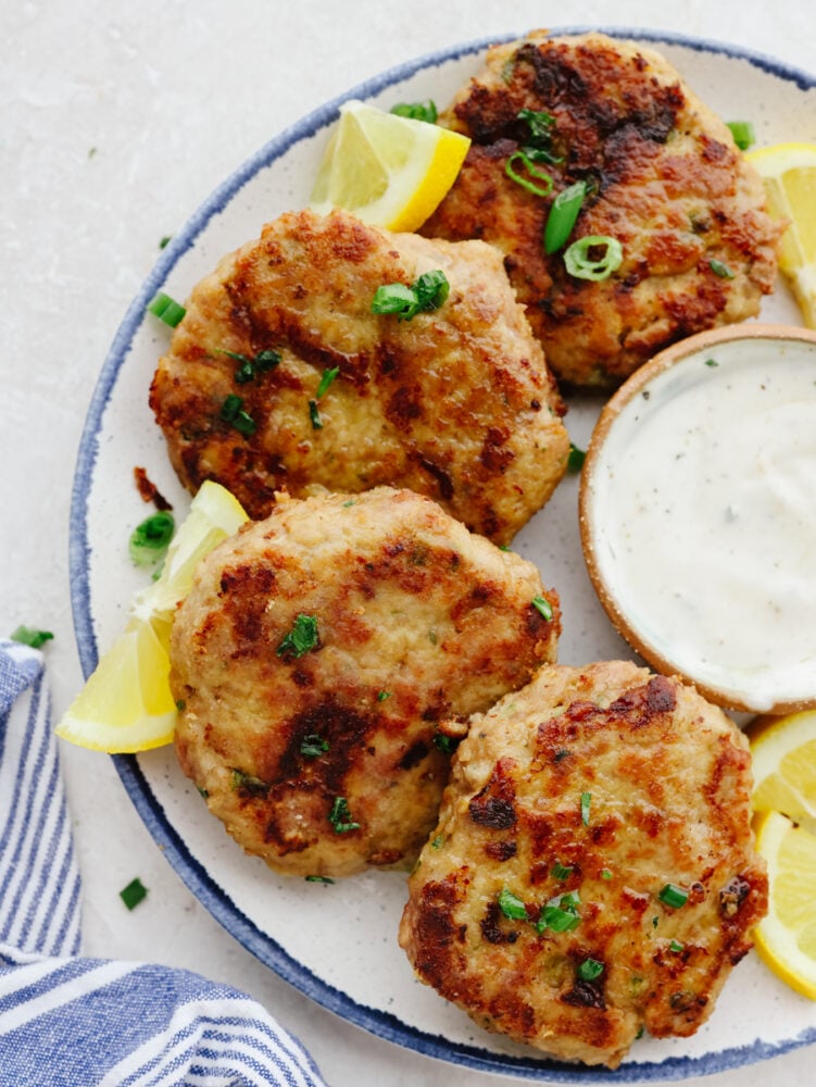 These chicken patties are crispy and perfectly browned on the outside and juicy and tender on the inside. They are a delicious addition to any meal for any occasion! Chicken patties on a platter with some lemons and tartar sauce.