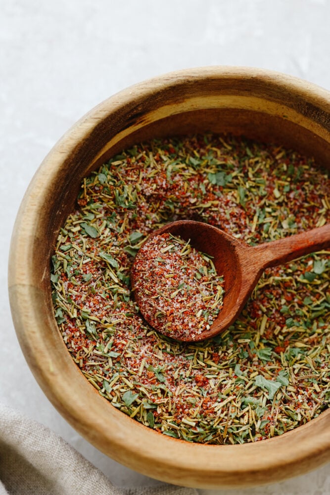 ade with delicious herbs and savory flavors, this chicken seasoning will make any piece of chicken taste absolutely incredible! It takes any chicken recipe to the next level. You will never buy store-bought seasoning again! A wooden bowl with a wooden spoon filled with chicken seasoning.