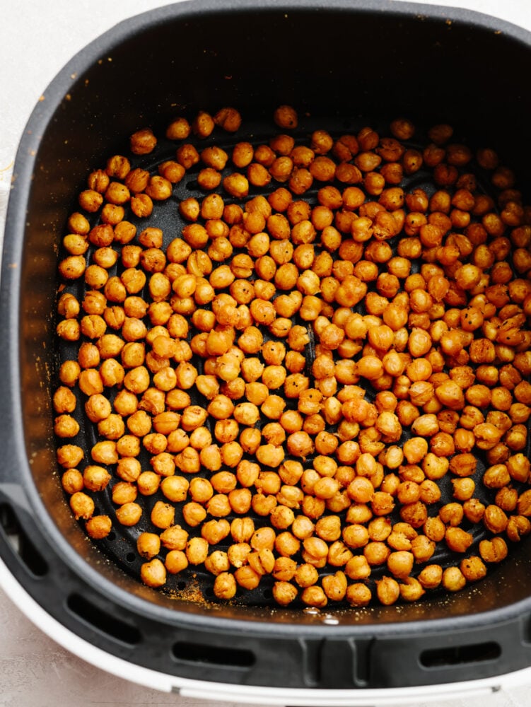 Air fryer chickpeas are crispy and flavored to perfection! With three different ways to season them, there will be a flavor for everyone. These crunchy, roasted chickpeas will become your new go-to snack! Roasted chickpeas in an air fryer basket.