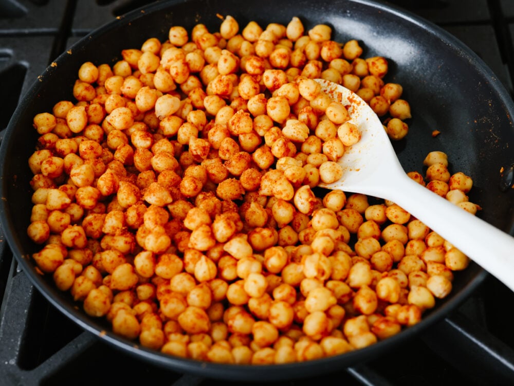 Chickpea tacos are a great way to get your daily protein and all the Tex-Mex flavors that you crave! These flavorful tacos are loaded with fresh veggies and topped off with a creamy cilantro drizzle! Seasoned chickpeas cooking in a skillet.
