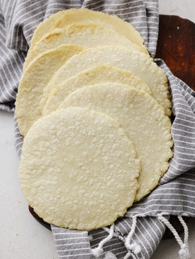 Homemade corn tortillas only have three ingredients and are a cinch to make! These guys are crispy on the edges, soft on the inside, and full of corn flavor. Corn tortillas in a stack on the counter.