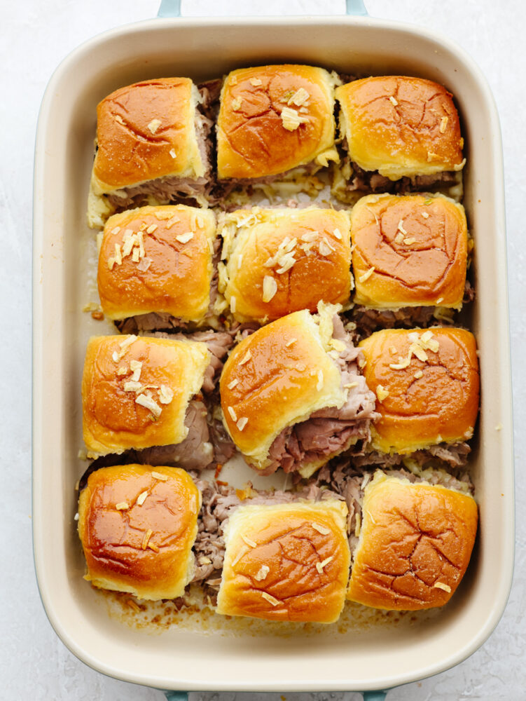 French dip sliders are filled with tender roast beef and melty provolone in bite-size form! It's a delicious pull-apart treat for a large crowd! A pan filled with 12 baked sliders.