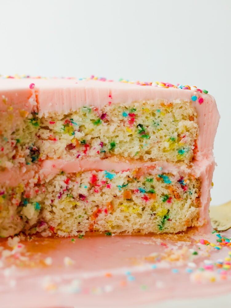 This light and fluffy homemade funfetti cake is perfect for every celebration! A white cake bursting with rainbow sprinkles is so delicious and will have everyone asking for a second slice. A side view of a slice of funfetti cake.