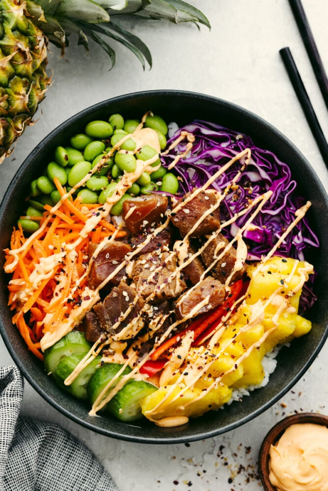 This Hawaiian poke bowl is fantastically fresh and full of healthy ingredients! Skip ordering this at a restaurant and make it at home in less than 15 minutes!ย A Hawaiian poke bowl with spicy aioli sauce on top.