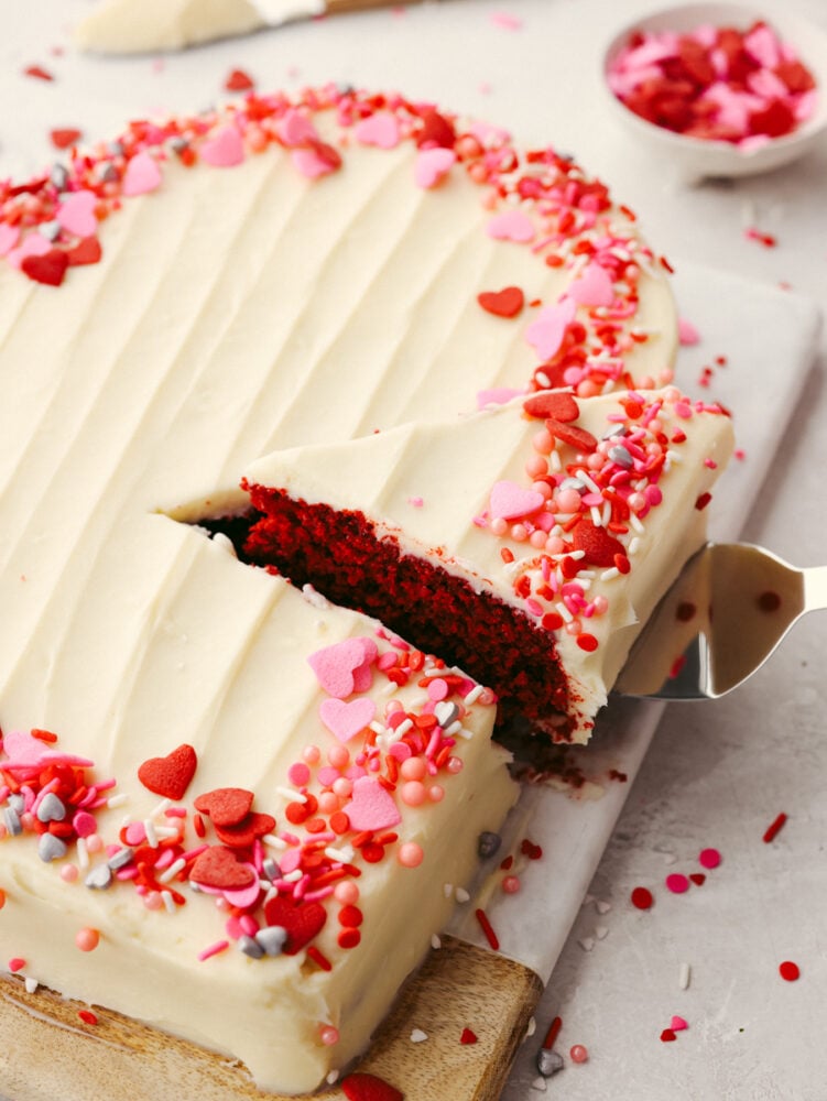 Festive and delicious, this heart-shaped cake is ready to impress your valentine! You can't go wrong with a red velvet cake topped with luscious cream cheese frosting! Using an icing spatula to take a slice of cake.