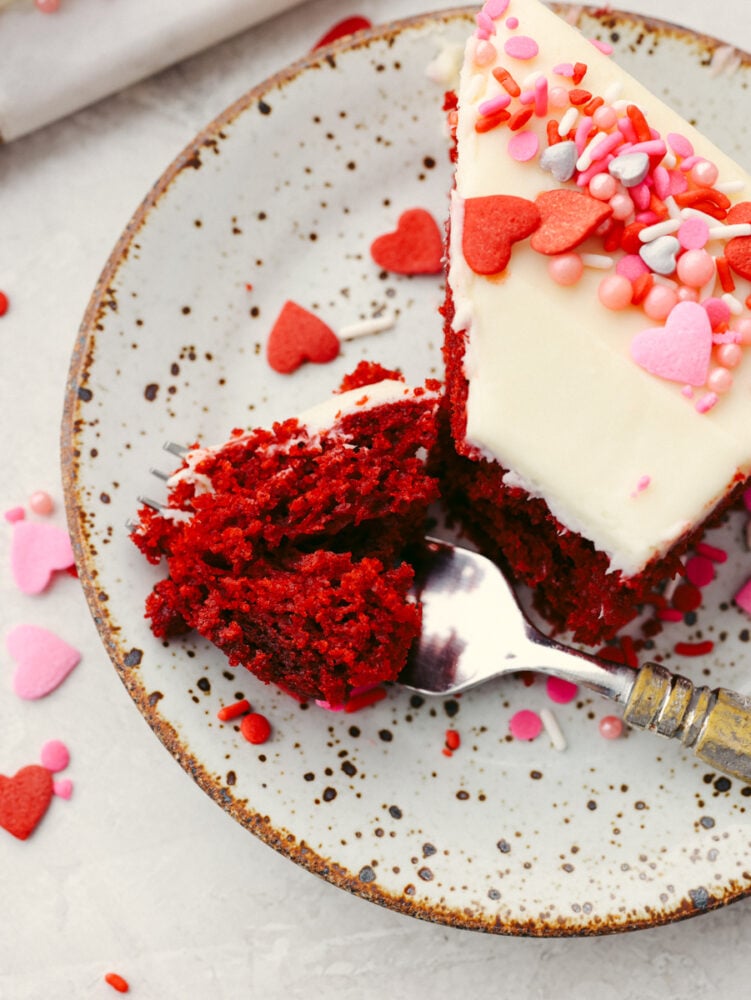 Festive and delicious, this heart-shaped cake is ready to impress your valentine! You can't go wrong with a red velvet cake topped with luscious cream cheese frosting! Taking a bite of red velvet cake slice.