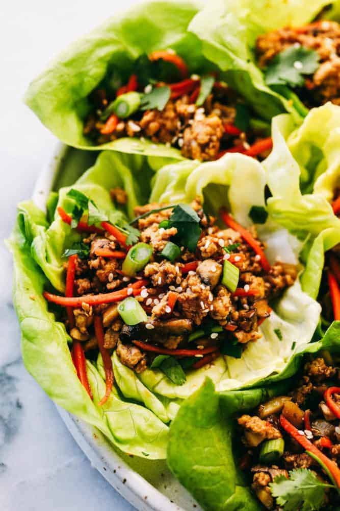 Asian turkey lettuce wrapsย are packed with intense flavorย from tender meat and seasoned, crunchy veggies. These light and tasty wraps are the perfect healthy appetizer or even dinner! A zoomed in picture of a lettuce wrap garnished with sesame seeds.