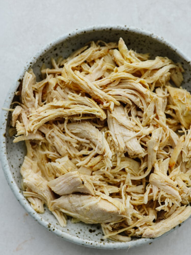 This instant pot shredded chicken is the solution to all of your chicken needs! It's seasoned, moist, and easy to shred, which makes it the perfect go-to recipe when you need shredded chicken for any dish. A bowl of shredded chicken.