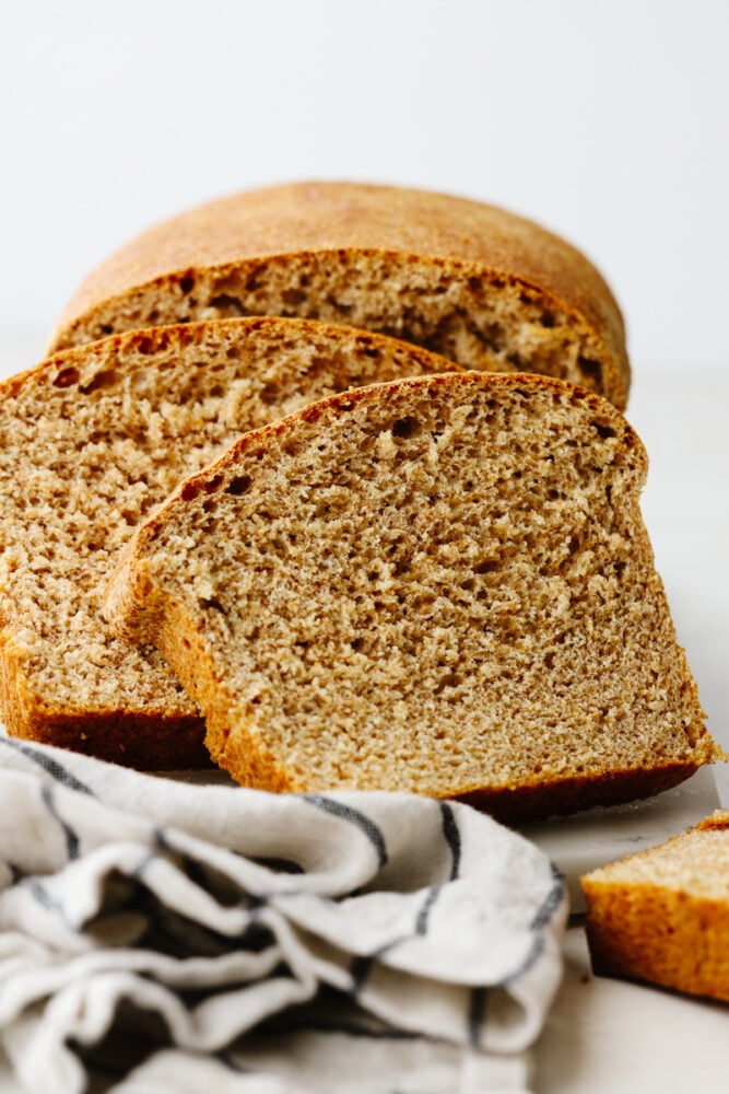 One slice of this amazing wheat bread and you'll be addicted! It's warm, soft, and tender, sweetened to perfection with honey! Closeup of 2 slices of bread.