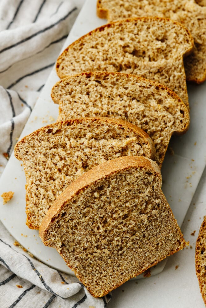 One slice of this amazing wheat bread and you'll be addicted! It's warm, soft, and tender, sweetened to perfection with honey! Multiple slices of wheat bread cut and laid on top of each other.