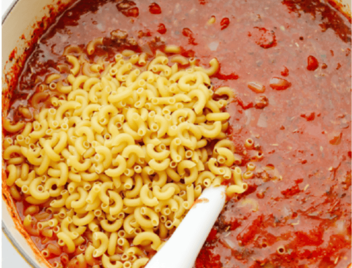 American Goulash is my kind of comfort food! It's rich, savory, and full of that cozy, tomato-y goodness. Itโs hearty, easy to make, and one bite will have you hooked just like my family is! Macaroni noodles and beef added into the pot ready to simmer together.