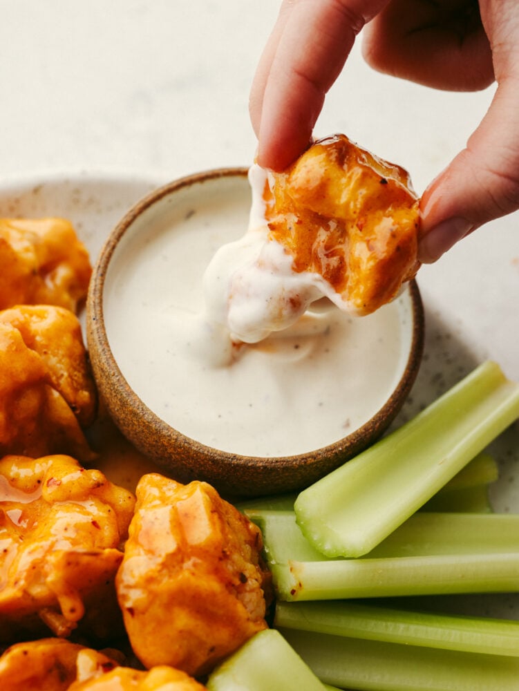 This low-carb take on wings is going to rock your world! Draped in a sticky-sweet honey buffalo sauce, these easy air fryer cauliflower wings are absolutely to die for! Dipping a cauliflower wing in ranch.