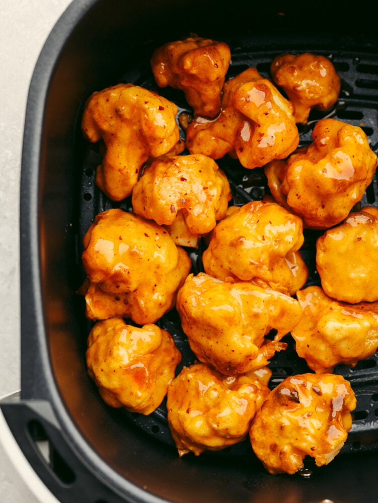 This low-carb take on wings is going to rock your world! Draped in a sticky-sweet honey buffalo sauce, these easy air fryer cauliflower wings are absolutely to die for! Honey buffalo cauliflower wings in the basket of an air fryer.