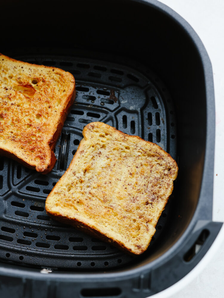 Air fryer french toast is simple and delicious! You can whip this up in less than 10 minutes, and your family will gobble it up so fast that it will fly off of your table! 2 pieces of cooked french toast in the air fryer.