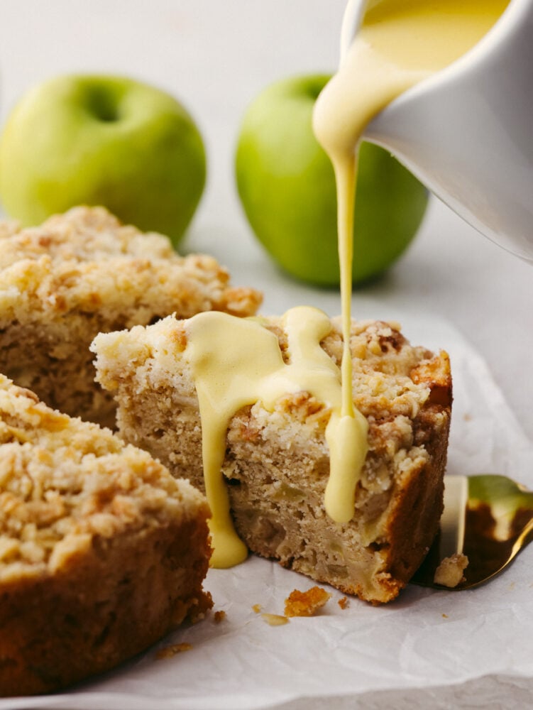 With a buttery streusel topping, Irish apple cake is tender and spiced to perfection. Drizzled with a warm custard sauce, this is one dessert you won't want to miss! Pouring custard sauce over a slice of Irish apple cake.