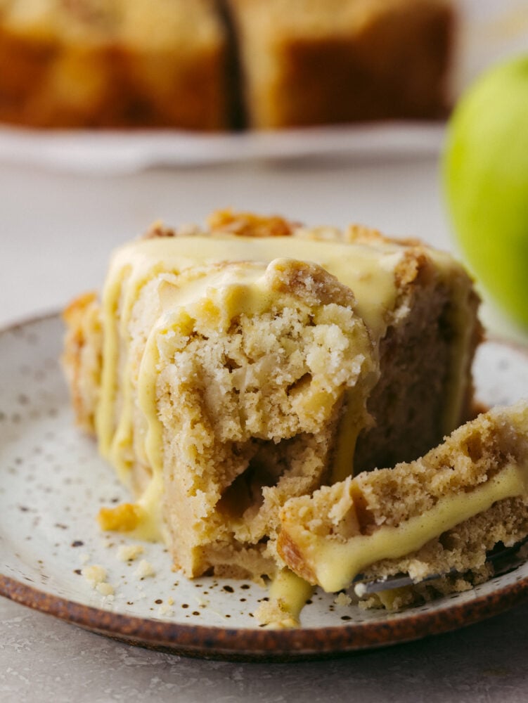 With a buttery streusel topping, Irish apple cake is tender and spiced to perfection. Drizzled with a warm custard sauce, this is one dessert you won't want to miss! Taking a bite of cake with a fork.