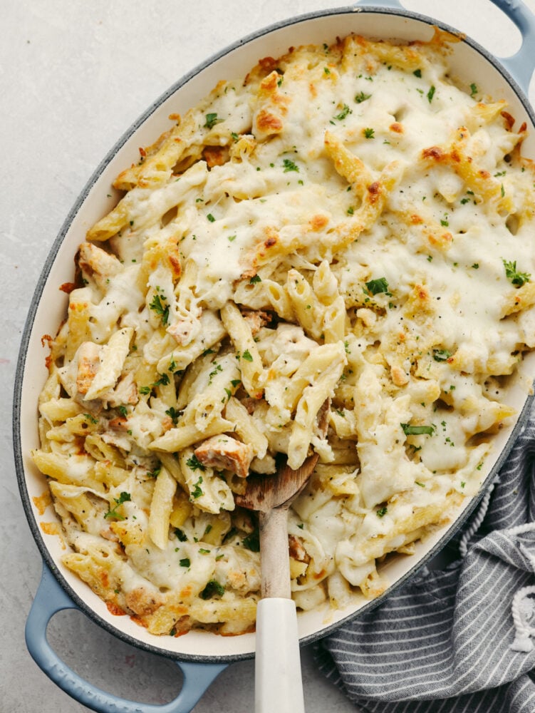 When I see Chicken Alfredo on a menu, I breathe a sigh of relief because I know my kids will actually eat it. I made this Chicken Alfredo Bake thatโs creamy, comforting, and ready in under 40 minutes. A baking pan filled with chicken and noodles and sauce with a wooden spoon.