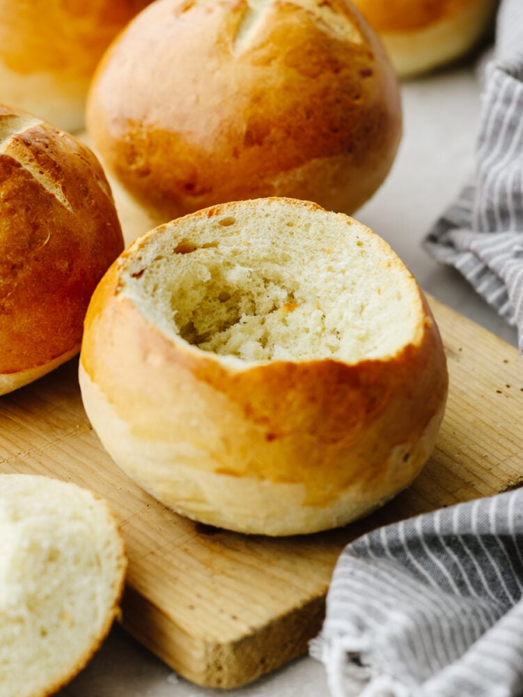 Homemade bread bowls are a simple and delicious way to take all of your soups to the next level! These bread bowls are perfectly crisp on the outside and soft and airy on the inside. A bread bowl on a wooden cutting board with the top cut out of it, ready for soup!