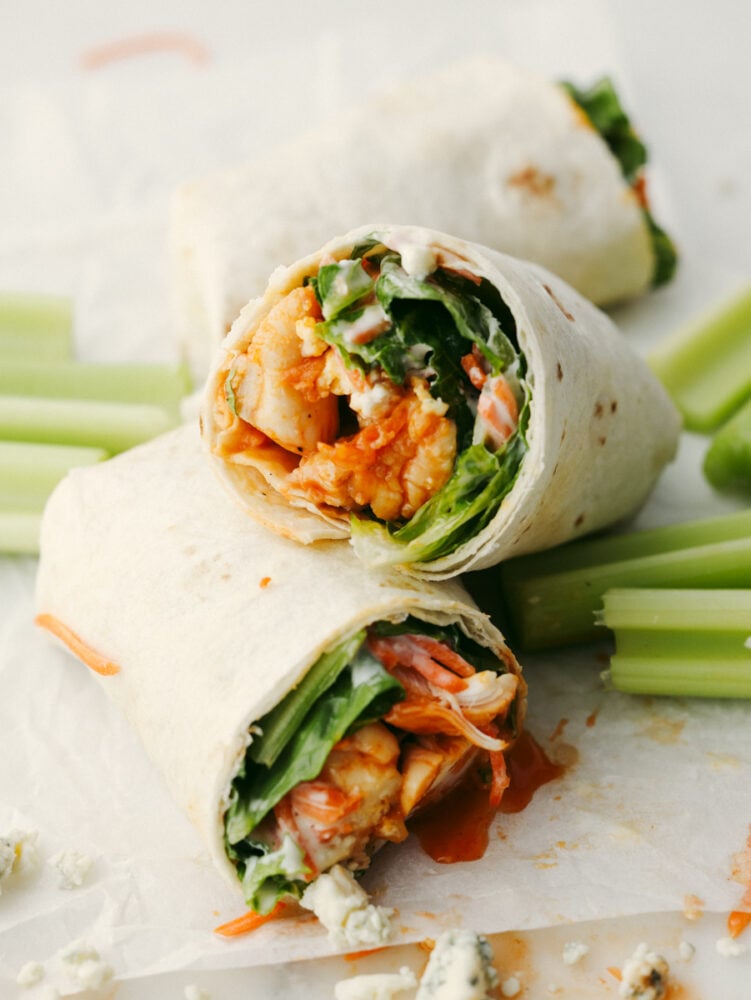 These honey buffalo chicken wraps are so healthy and delicious! They're loaded with a sweet buffalo sauce, ranch, bleu cheese, and all of your favorite veggies for a lunch you'll love! A honey buffalo chicken wrap, pictured alongside celery.