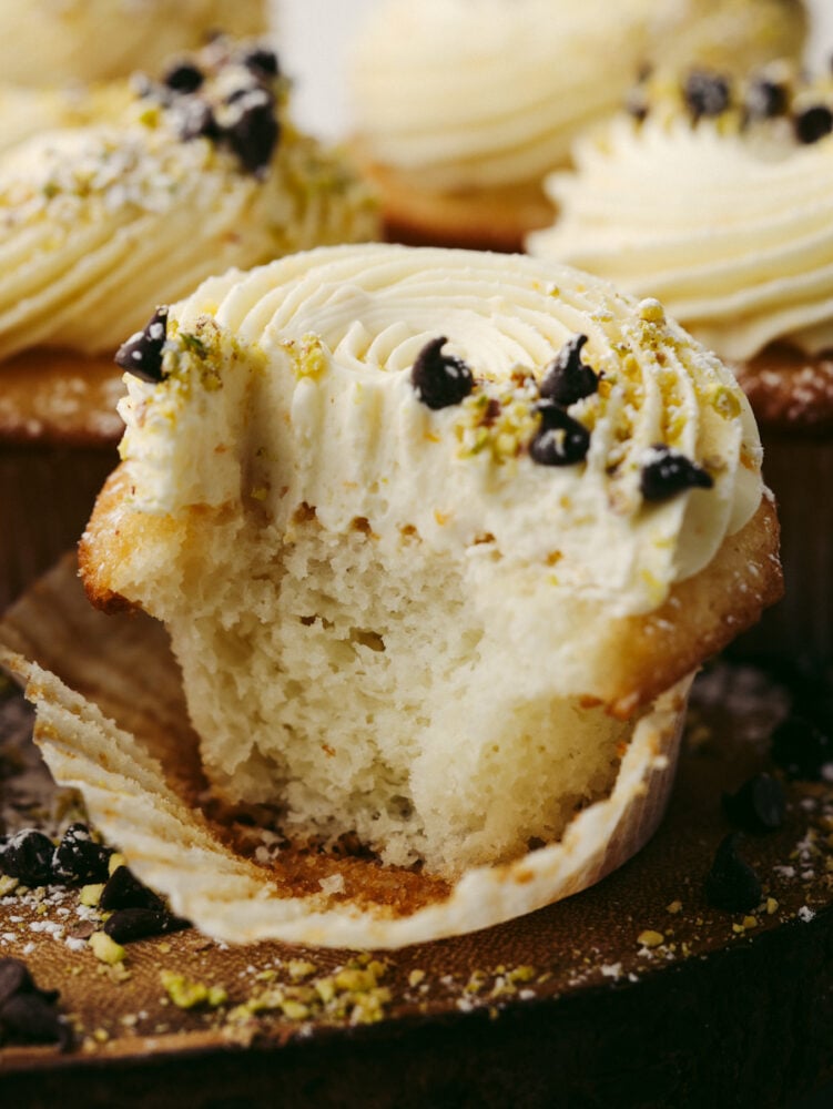 All the cannoli flavors you love in a bite-sized cupcake! Cannoli cupcakes are moist and tender with the most delicious mascarpone whipped cream frosting! Closeup of cannoli cupcake cut in half.