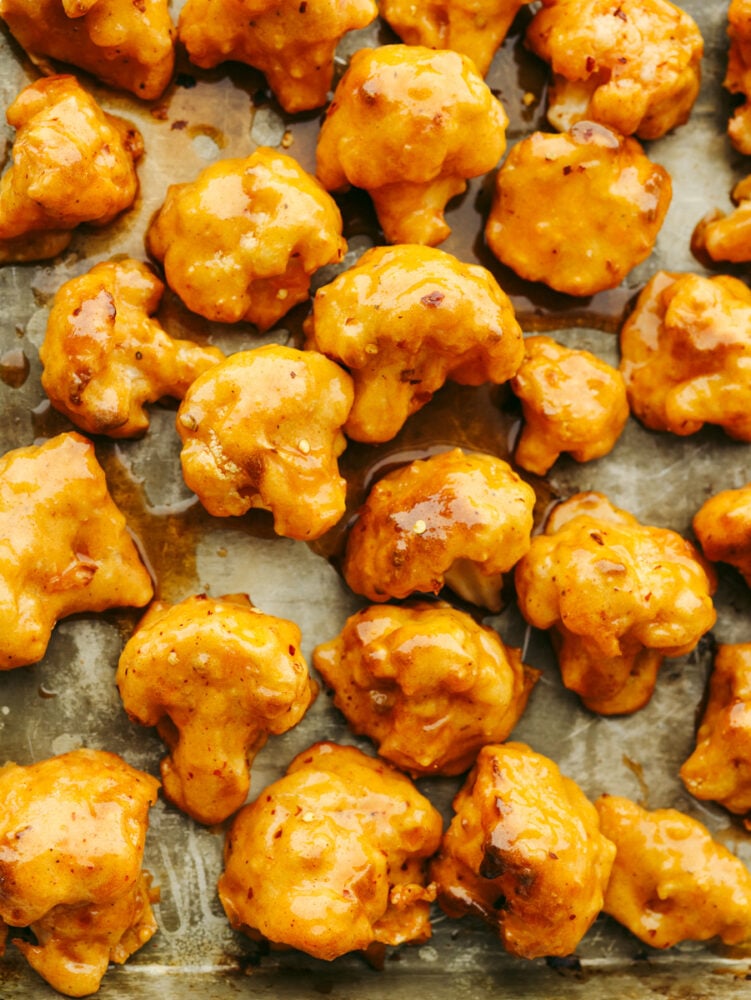 This healthier take on wings is insanely delicious! Coated in a delicious honey buffalo sauce, these cauliflower wings are so good that you will forget that you are even eating a vegetable! Baked cauliflower, coated in sauce on a baking sheet.