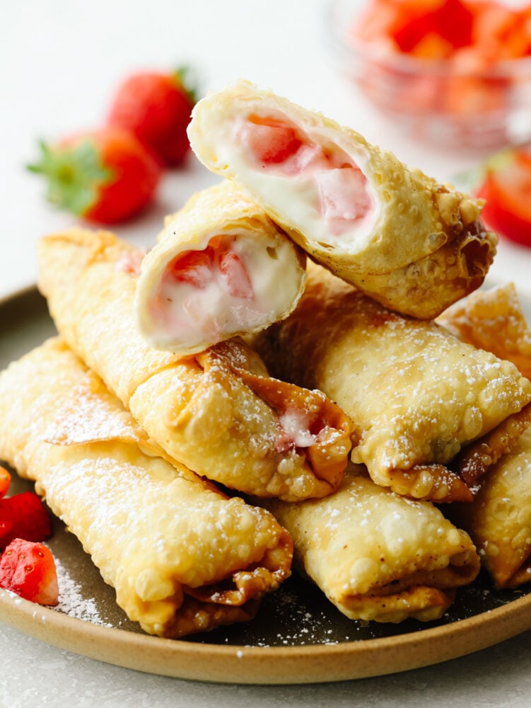 Crispy on the outside with a creamy, strawberry filling on the inside, these cheesecake egg rolls are the BEST. Your guests will eat one and won't be able to stop! A stack of cheesecake egg rolls. The one on topis cut in half so that you can see the strawberry cheesecake filling inside.