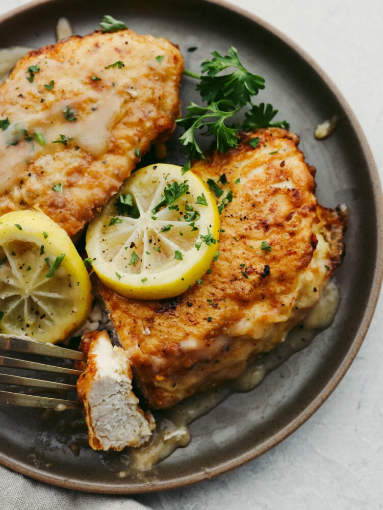 If youโve never had Chicken Francese, youโre in for a treat! Lightly breaded chicken, pan-fried to golden perfection, then bathed in a bright, buttery lemon sauce thatโs totally irresistible. Chicken Francese on a plate that is garnished and ready to eat.