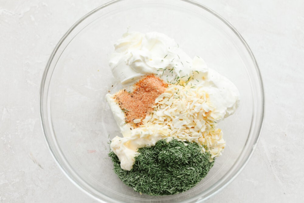 This delicious dill dip is easy and goes with everything. It is creamy and full of flavor and will be ready to eat in less than 5 minutes! If you are a dill pickle lover like me then you are going to be bringing this to every party and get-together! A bowl filled with ingredients ready to be mixed.