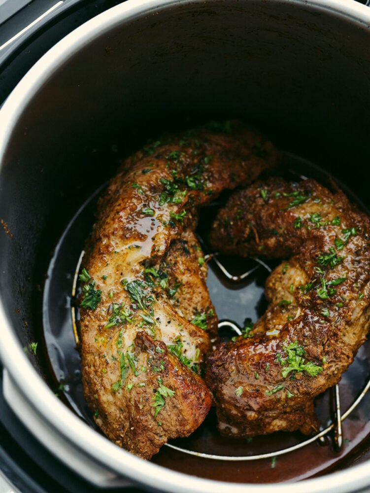 This juicy Instant Pot pork tenderloin is the perfect choice for dinner! It cooks up in 15 minutes and is full of so much flavor! 2 cuts of pork tenderloin on a trivet in an Instant Pot.