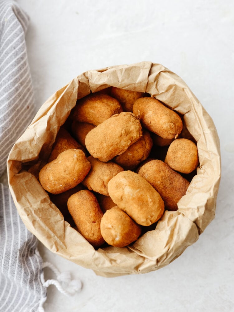Irish potato candy is a no-bake treat filled with cream cheese and coconut flakes and then topped with cinnamon. These aren't your regular potatoes, they are candy, and I am here for it! The top view of a brown paper bag filled with potato candy.