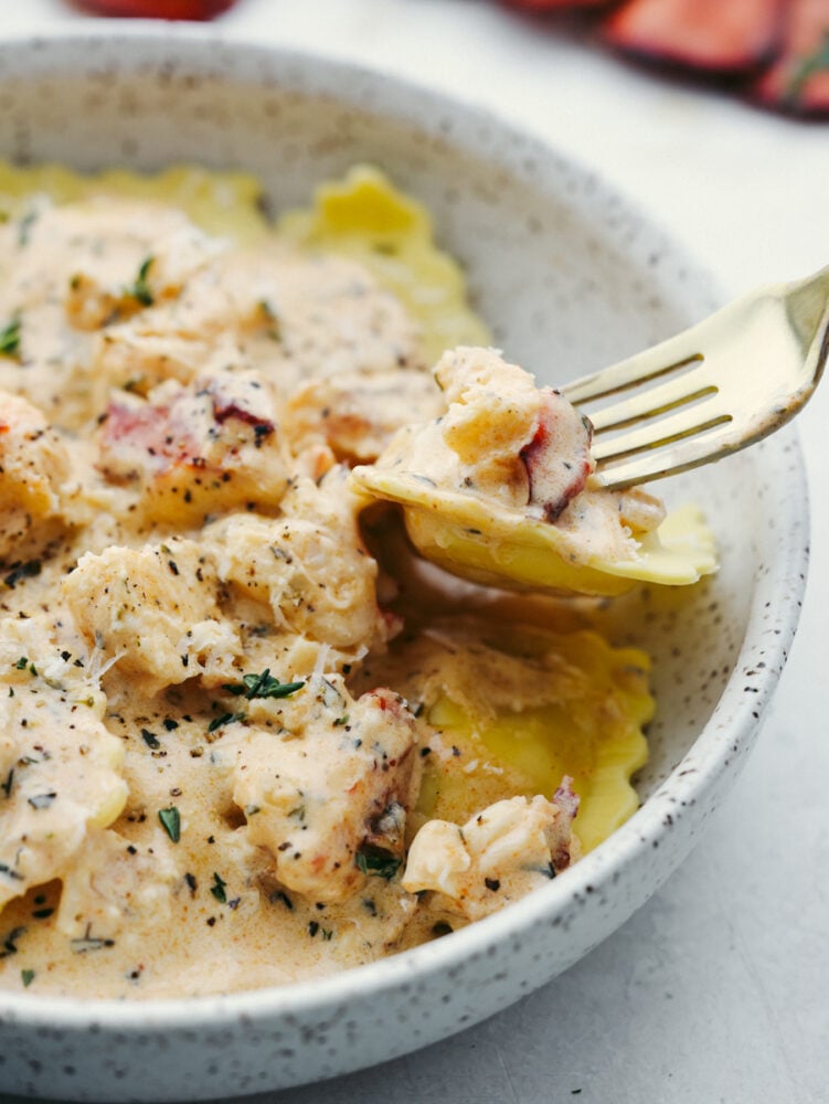 Lobster ravioli sauce is rich and creamy, full of fresh herbs and garlic! It's bursting with flavor and the perfect addition to all of your favorite pasta dishes. Picking up lobster and ravioli with a fork.