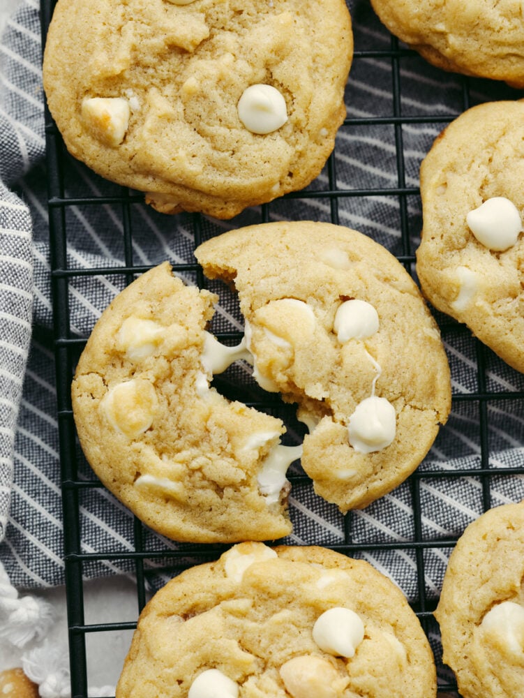 This classic white chocolate macadamia nut cookie is one that everyone loves! This recipe is simple and easy and whips up a huge batch of soft, thick, and chewy cookies that you can share with everyone! A cookie broken in half with melted white chocolate chips.