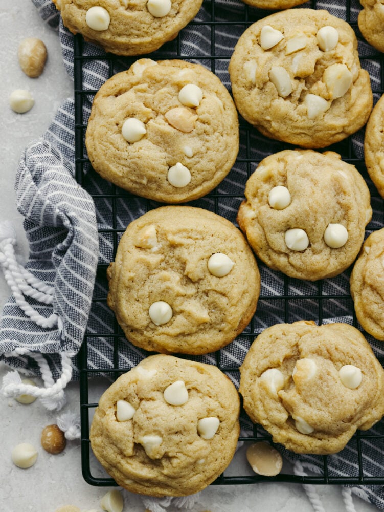 This classic white chocolate macadamia nut cookie is one that everyone loves! This recipe is simple and easy and whips up a huge batch of soft, thick, and chewy cookies that you can share with everyone! The top view of macadamia nut cookies on a cooling rack.