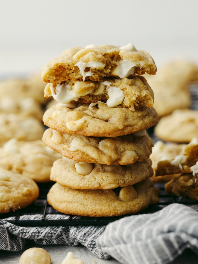 This classic white chocolate macadamia nut cookie is one that everyone loves! This recipe is simple and easy and whips up a huge batch of soft, thick, and chewy cookies that you can share with everyone! A stack of macadamia nut cookies on a cooling rack.