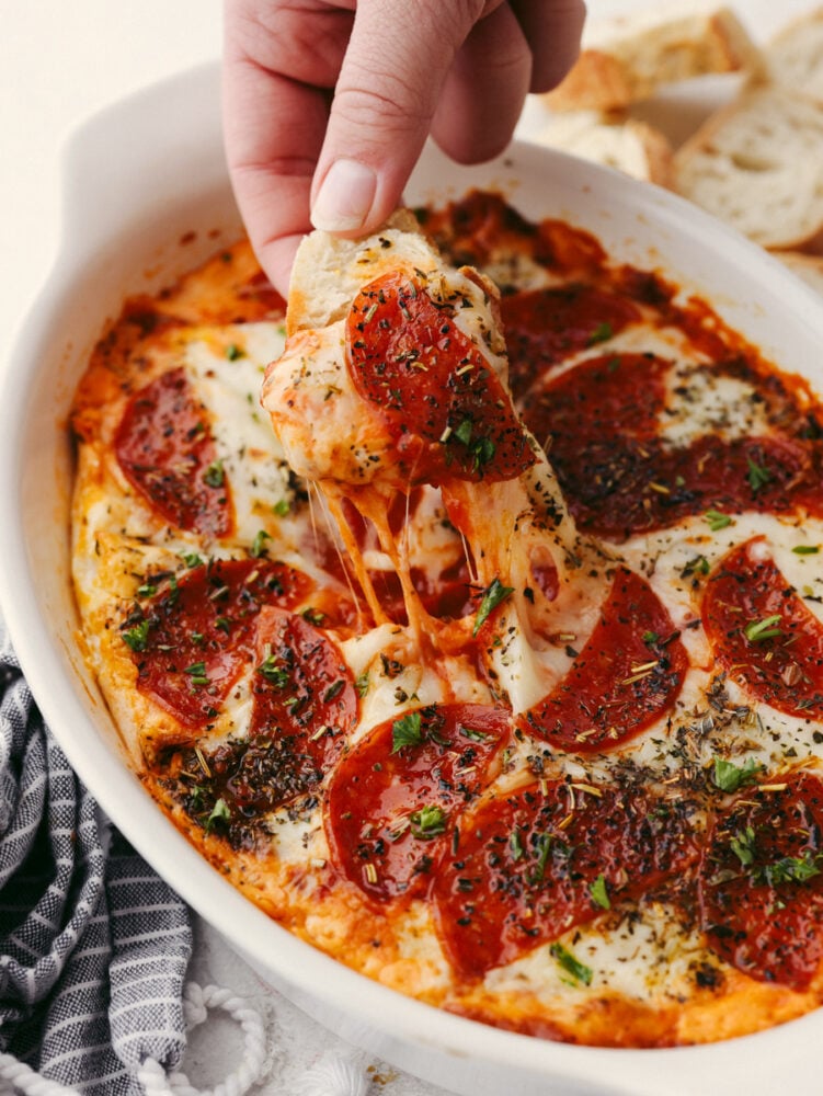 Pepperoni pizza dip is ooey-gooey cheese mixed with flavorful pizza seasonings and topped with delicious pepperoni. It is baked until it's hot and bubbly, and it will be the perfect appetizer at any party! A dish filled with pepperoni pizza dip.