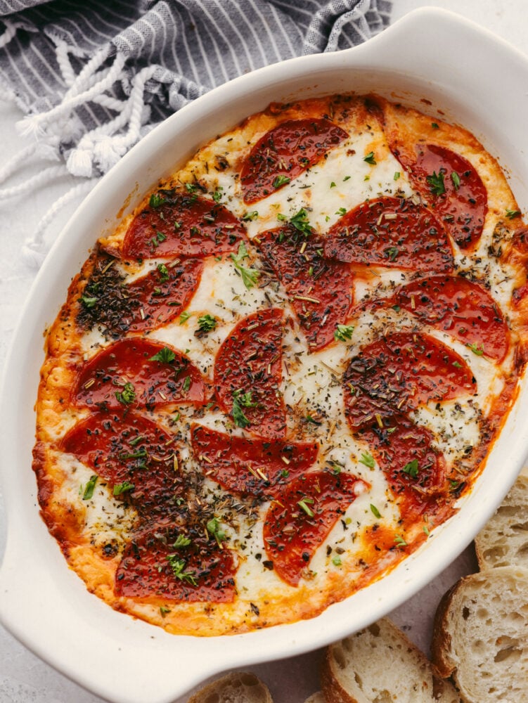 Pepperoni pizza dip is ooey-gooey cheese mixed with flavorful pizza seasonings and topped with delicious pepperoni. It is baked until it's hot and bubbly, and it will be the perfect appetizer at any party! A top view of pepperoni pizza dipped baked and in a casserole dish.