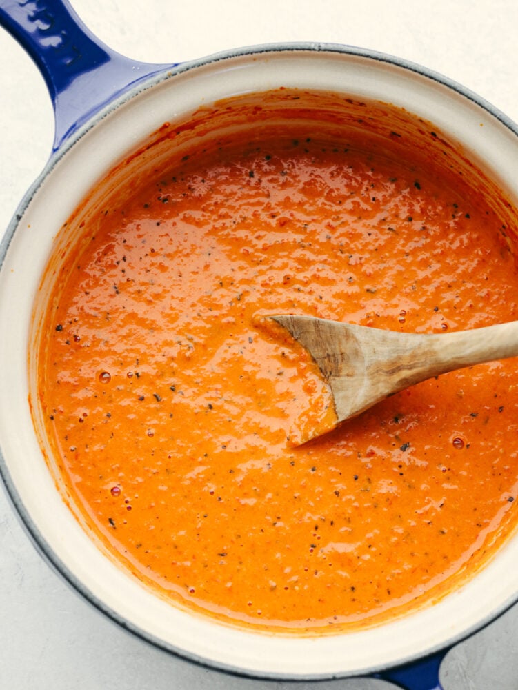 Level up pasta night with this irresistible roasted red pepper sauce! It's creamy, cheesy, and delicious with smoky, sweet spice. Be sure to make enough for seconds, your family won't be able to get enough! Top-down view of roasted red pepper sauce in a white and blue pan.